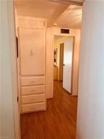 Corridor with light wood-style flooring and a textured ceiling