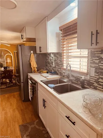 Kitchen with white cabinets, light wood-style flooring, dishwasher, tasteful backsplash, and a textured ceiling