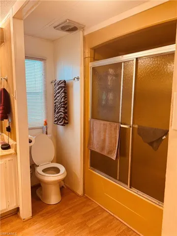 Full bath with shower / bath combination with glass door, light wood-style floors, and vanity