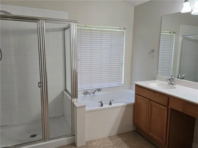 Full bath featuring vanity, a stall shower, a bath, and light tile patterned floors