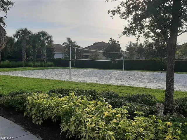 View of home's community with volleyball court, a yard, and a water view