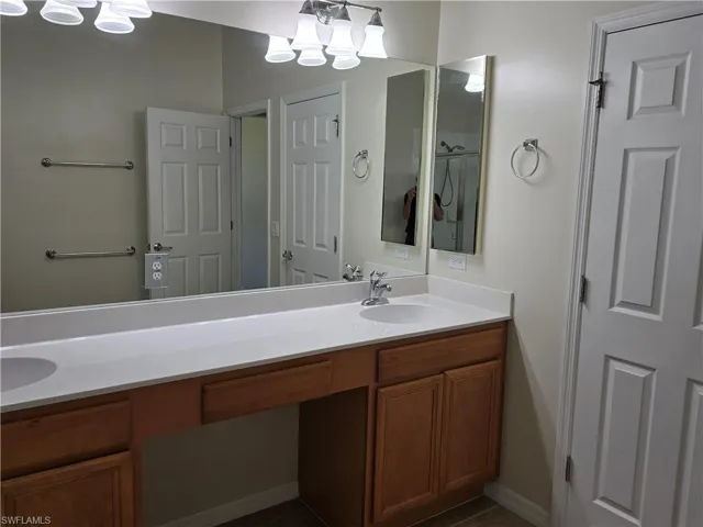 Full bathroom with double vanity, a chandelier, and dark tile patterned floors