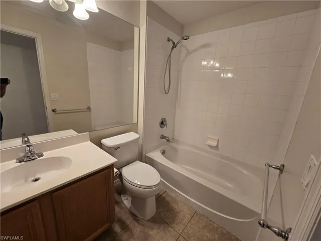 Bathroom with vanity,  shower combination, and dark tile patterned flooring