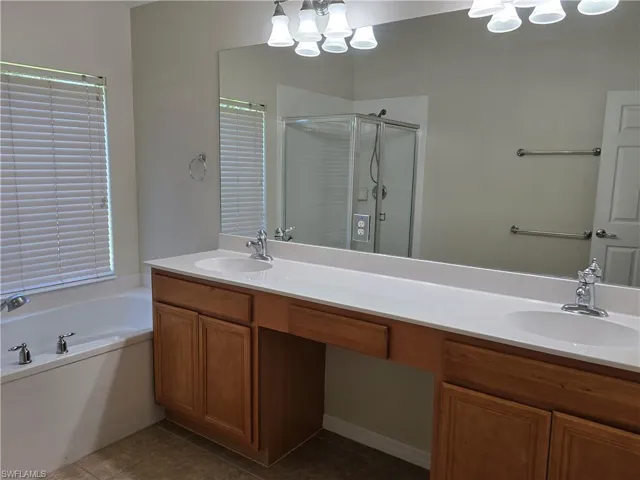 Full bath with a shower stall, a garden tub, dark tile patterned flooring, and double vanity