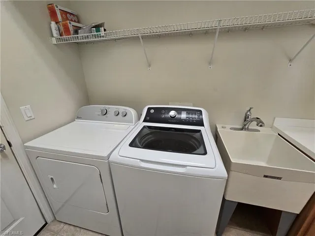 Laundry area with washer and dryer and light tile patterned flooring