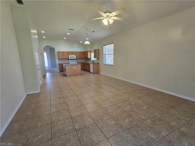 Kitchen with open floor plan, arched walkways, light tile patterned floors, a center island, and ceiling fan