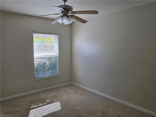 Carpeted empty room featuring baseboards and a ceiling fan