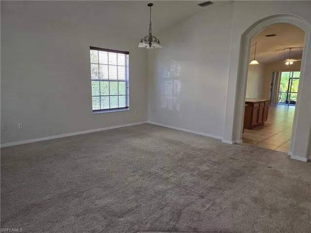 Family room featuring vaulted ceiling, arched walkways, light colored carpet, and a chandelier