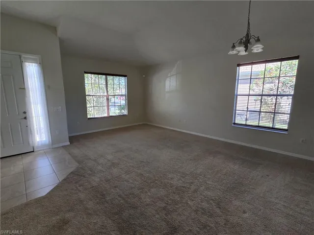 Entrance with light carpet, light tile patterned floors, vaulted ceiling, and a chandelier