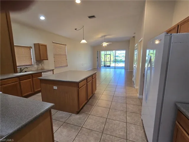Kitchen with white appliances, brown cabinetry, a ceiling fan, tasteful backsplash, and countertops