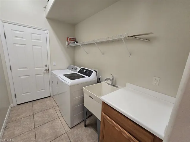 Laundry area with light tile patterned floors and separate washer and dryer