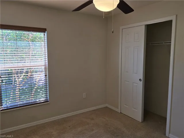 Unfurnished bedroom featuring light carpet, a closet, and a ceiling fan