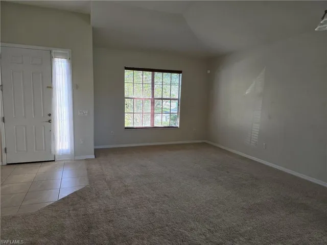 Family room with light tile patterned floors, light carpet, and vaulted ceiling