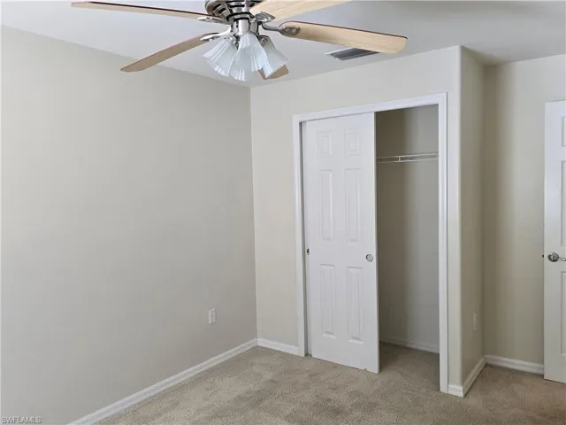 Unfurnished bedroom with light colored carpet, a closet, and ceiling fan