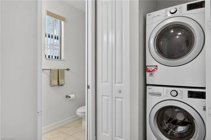 Laundry area featuring stacked washing machine and dryer and baseboards