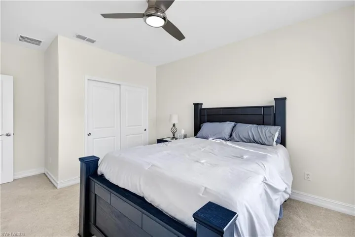 Bedroom featuring light colored carpet, ceiling fan, and a closet