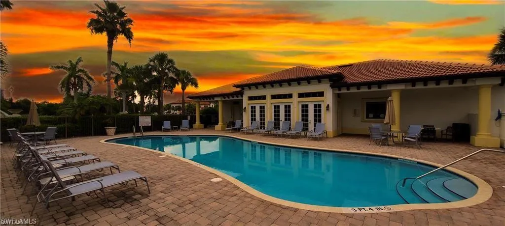 Pool at dusk featuring a patio area and a community pool