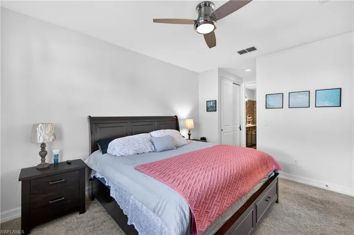 Bedroom with light carpet, a ceiling fan, connected bathroom, and a closet