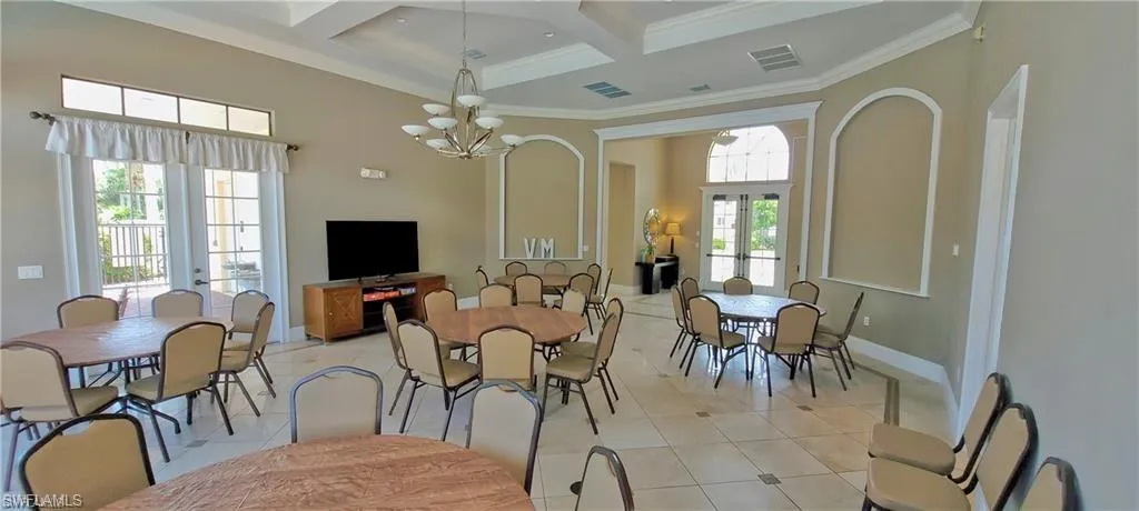 Dining area with coffered ceiling, light tile patterned floors, crown molding, and suspended lighting