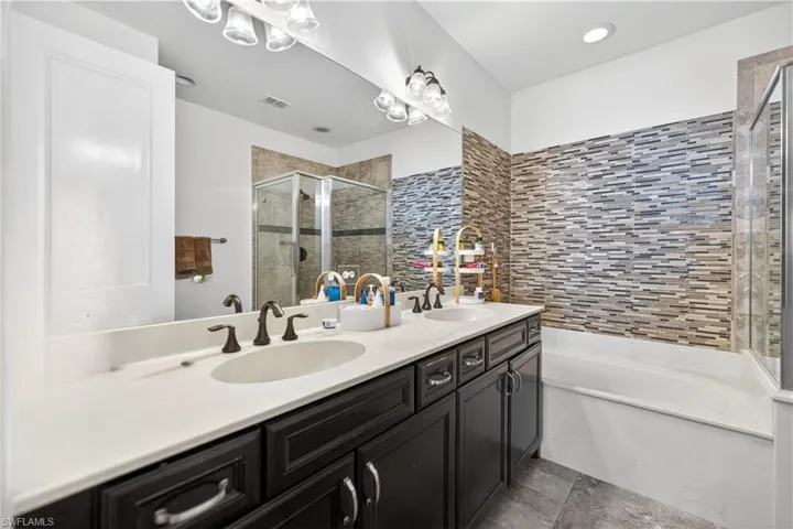 Bathroom featuring double vanity, a bath, and a stall shower