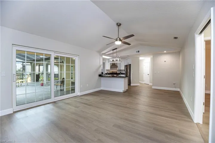 Unfurnished living room featuring a textured ceiling, vaulted ceiling, ceiling fan, and light hardwood / wood-style flooring