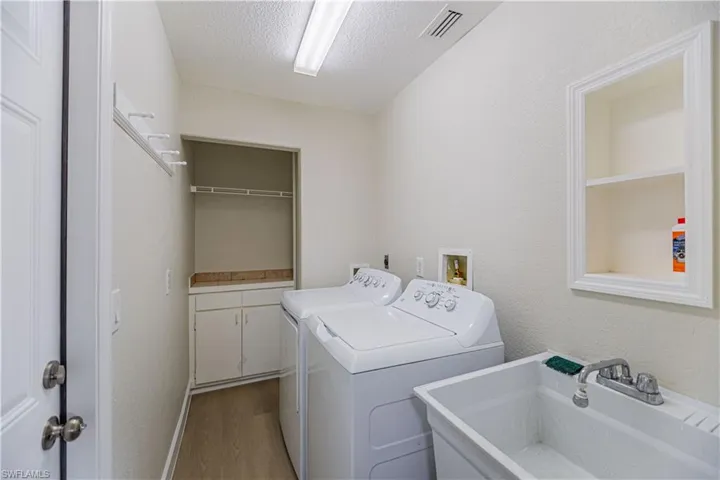 Clothes washing area with a textured ceiling, light hardwood / wood-style floors, sink, and independent washer and dryer