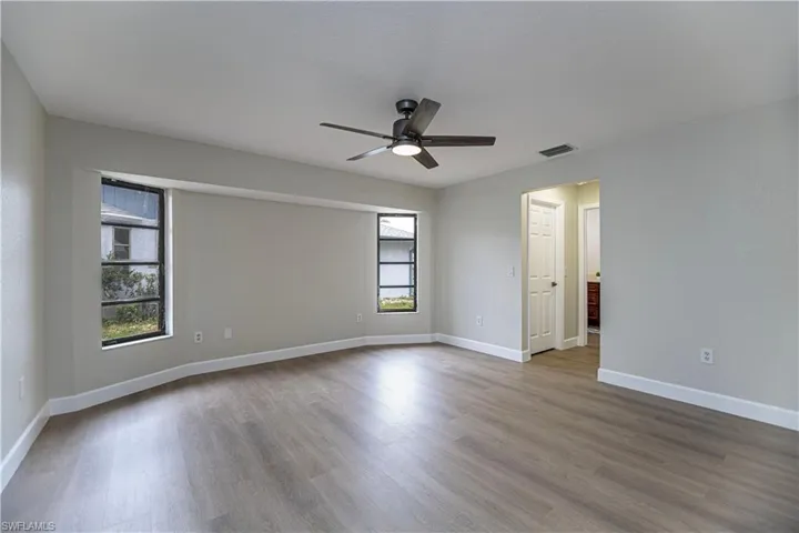 Spare room featuring ceiling fan, light wood-type flooring, and plenty of natural light