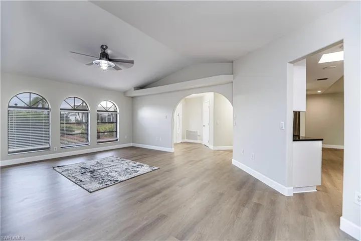 Unfurnished living room featuring ceiling fan, light hardwood / wood-style flooring, and vaulted ceiling