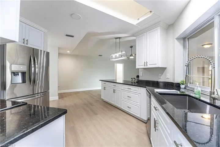 Kitchen featuring sink, white cabinets, light hardwood / wood-style flooring, appliances with stainless steel finishes, and decorative light fixtures