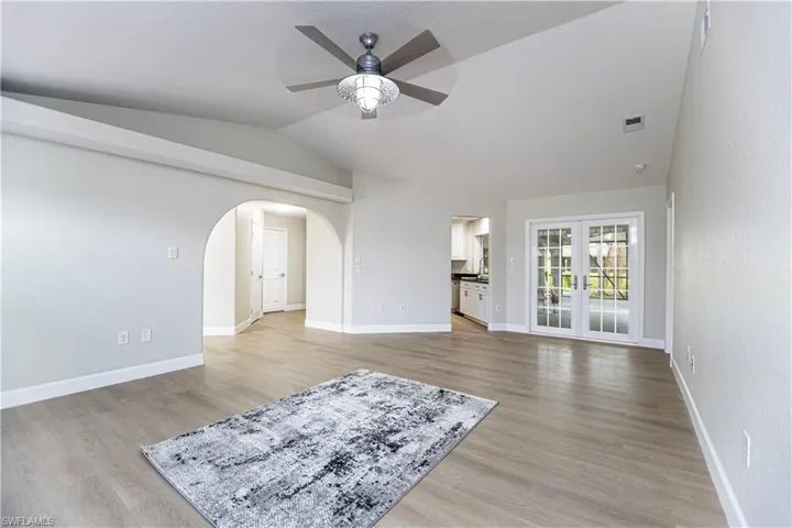 Living room with light wood-type flooring, lofted ceiling, ceiling fan, and french doors