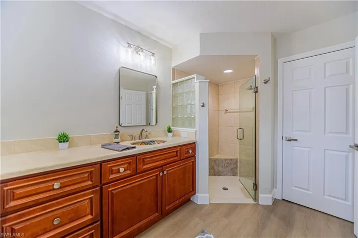 Bathroom featuring vanity, wood-type flooring, an enclosed shower, and a textured ceiling