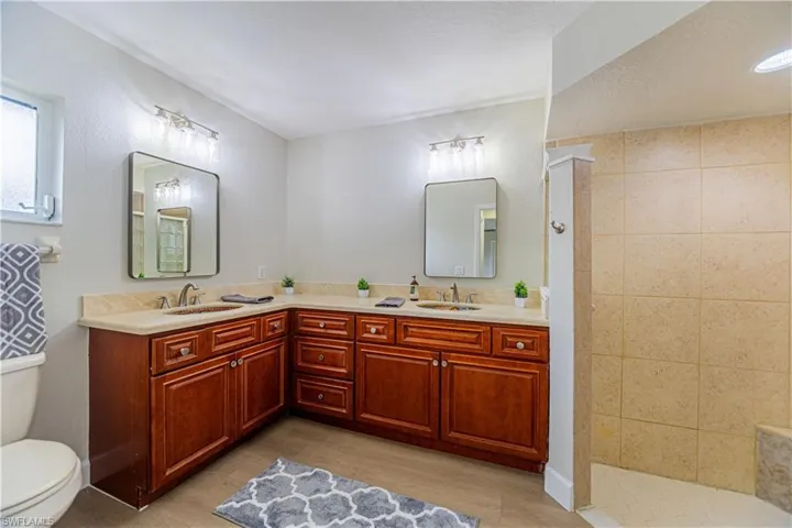 Bathroom with wood-type flooring, a textured ceiling, a shower, vanity, and toilet