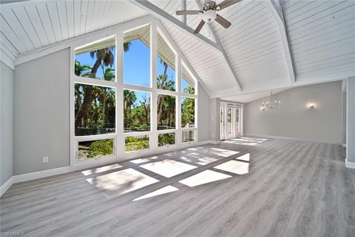 * Flooring has been removed. Unfurnished living room featuring high vaulted ceiling, wooden ceiling, ceiling fan with notable chandelier, light hardwood / wood-style flooring, and beam ceiling