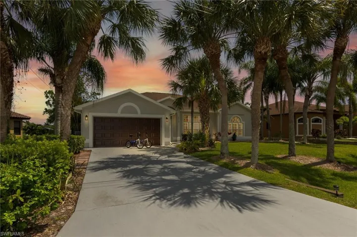 View of front of house with a lawn, an attached garage, driveway, and stucco siding