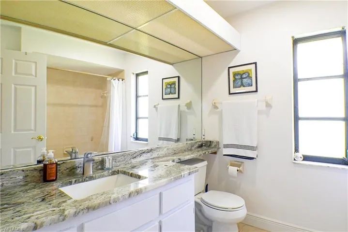 Bathroom featuring vanity with extensive cabinet space and toilet