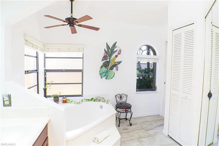 Bathroom featuring ceiling fan, vanity, a bath, and tile flooring