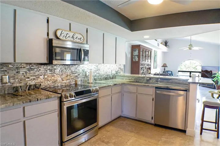 Kitchen featuring ceiling fan, tasteful backsplash, light tile floors, sink, and appliances with stainless steel finishes