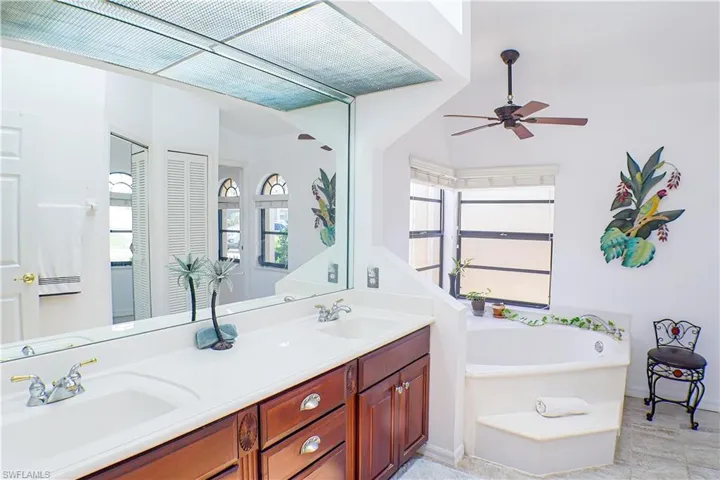 Bathroom featuring tile flooring, double sink vanity, ceiling fan, and a bathtub