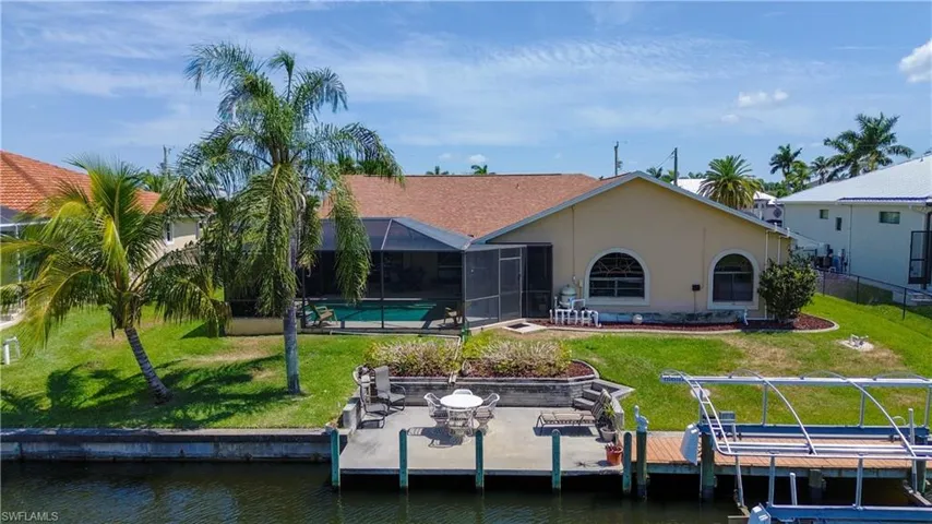Back of house with a patio, a lanai, a water view, and a yard