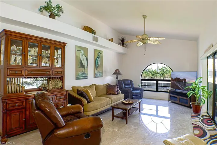 Living room featuring high vaulted ceiling, ceiling fan, and light tile floors