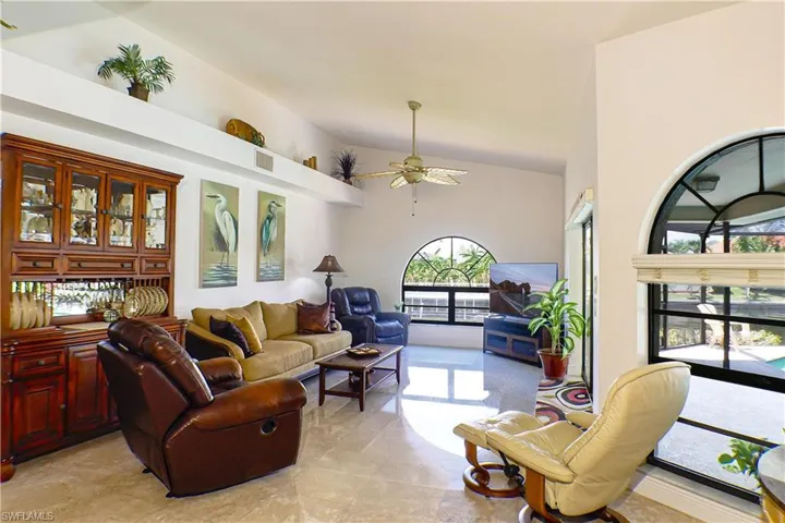 Living room with a high ceiling, ceiling fan, and light tile flooring