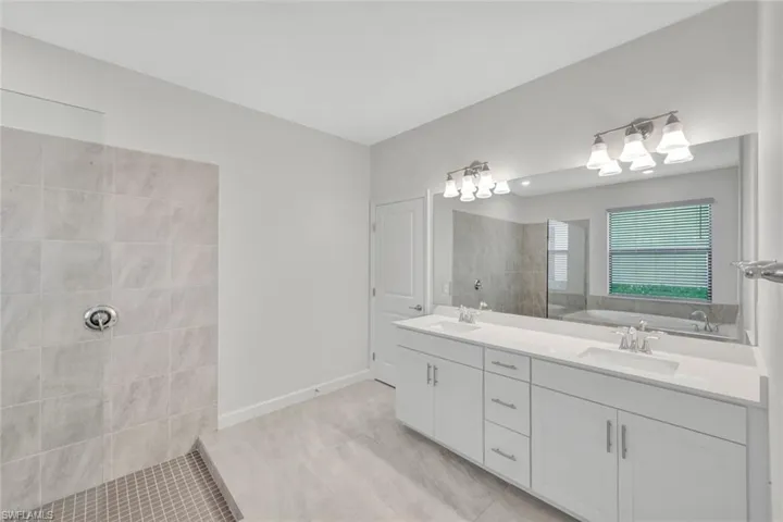 Full bathroom with double vanity, walk in shower, and light tile patterned floors