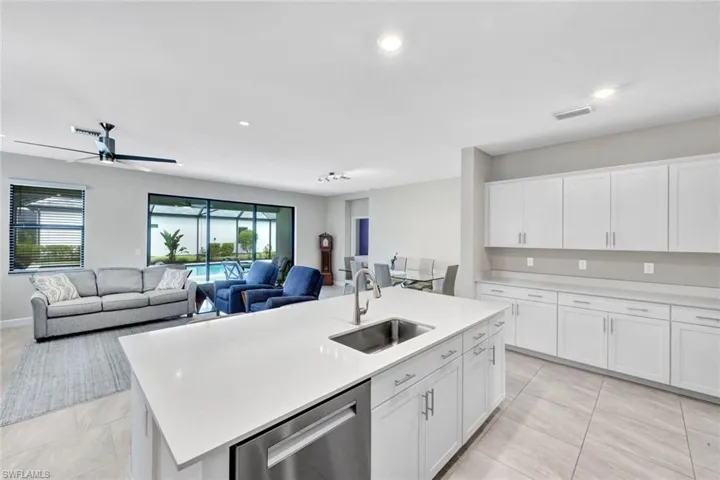 Kitchen featuring white cabinetry, stainless steel dishwasher, an island with sink, ceiling fan, and recessed lighting