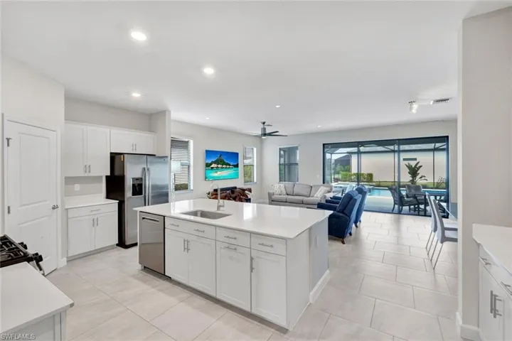 Kitchen with white cabinets, a center island with sink, dishwasher, ceiling fan, and open floor plan