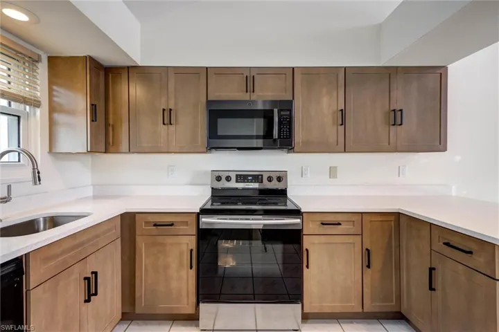 U-shaped kitchen with wood-finish cabinetry, stainless steel appliances, and light-toned countertops