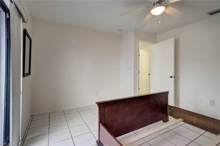 White tile flooring, white walls, and a ceiling fan with integrated lighting