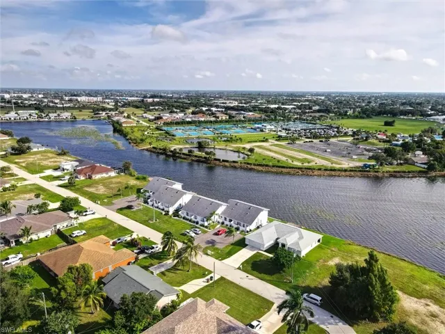 Waterfront canal property with residential homes, paved roads, and green spaces