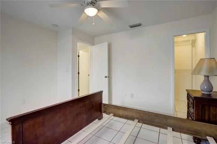 White tile flooring, white walls, and a ceiling fan with integrated lighting