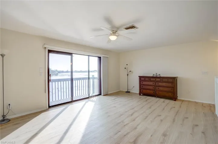 Sliding glass doors opening to an outdoor deck, wood-finish flooring, ceiling fan with integrated lighting