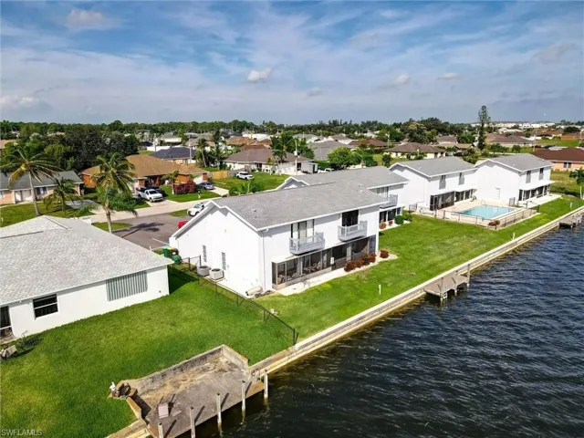 Waterfront property featuring a private boat dock, in-ground swimming pool, screened-in patio, and upper-level balcony